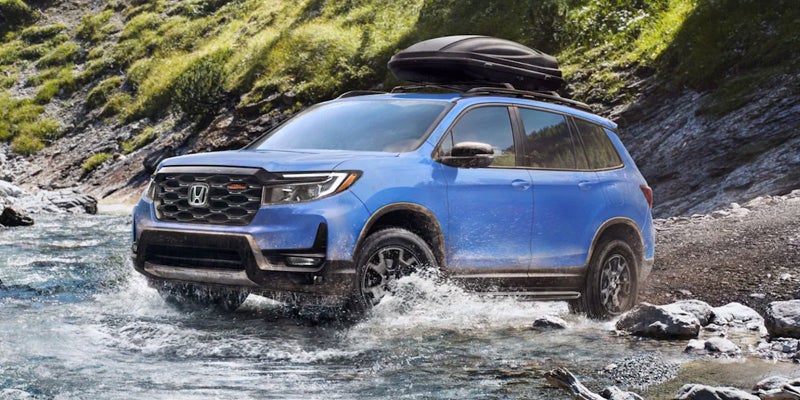 A photo of a blue 2024 Honda Passport driving through a stream.