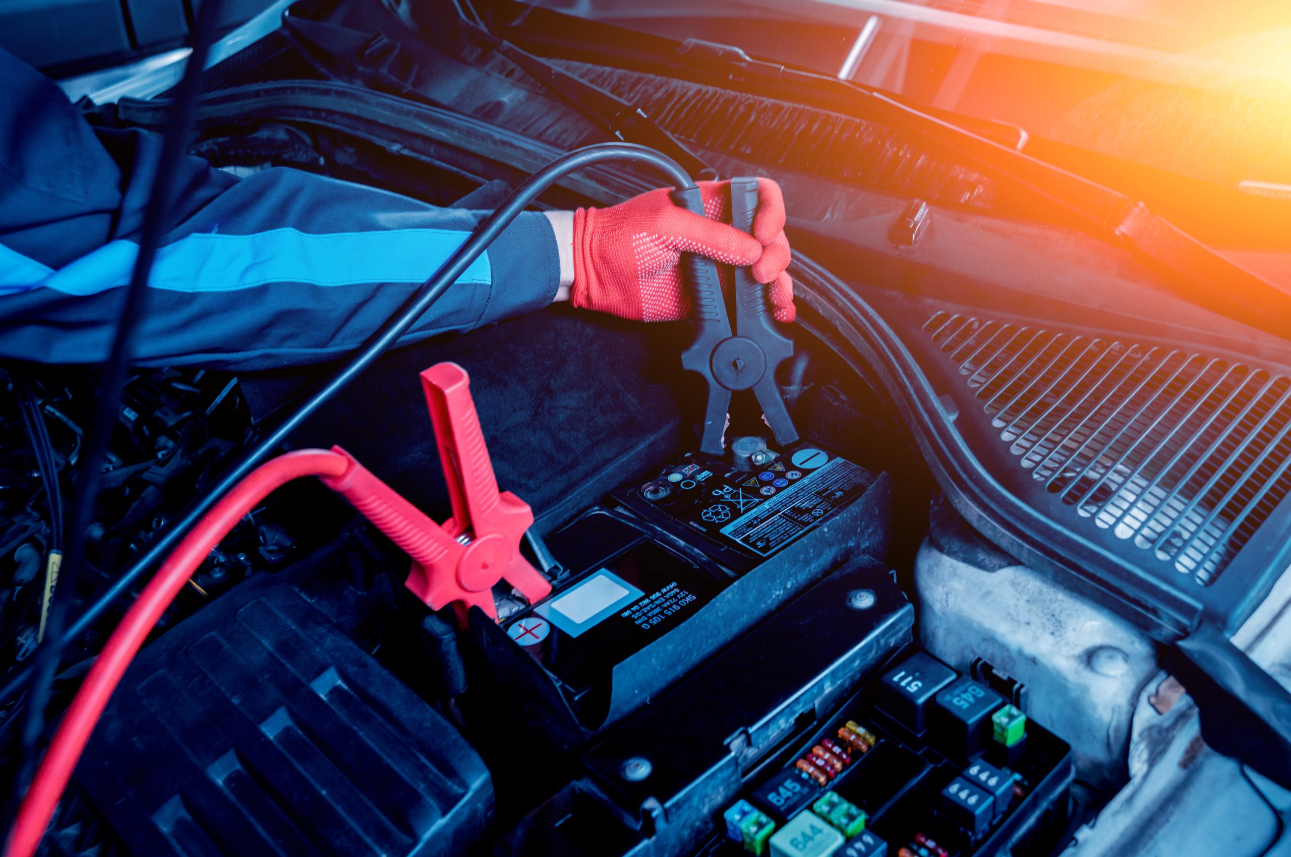 A photo of a service technician jumpstarting a car battery