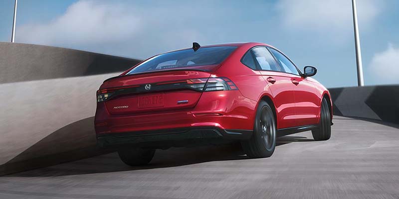 A red 2024 Honda accord driving down a highway.