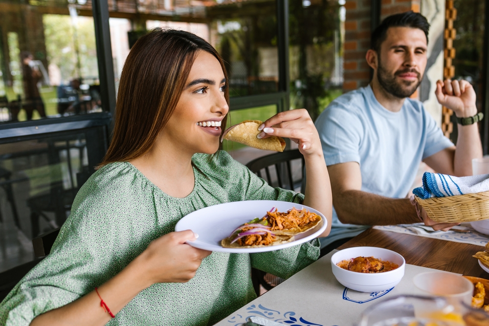 A photo of a woman at a restaraunt eating a taco