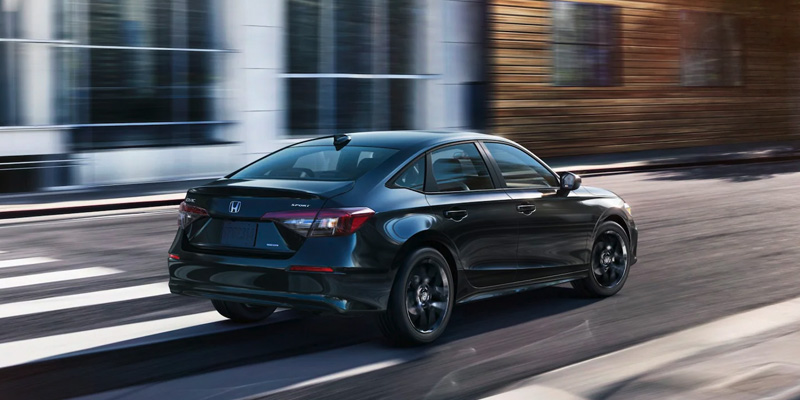 A black 2025 Honda Civic driving down a city street
